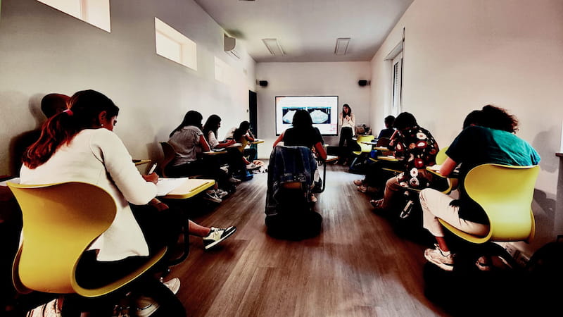 An audience of students seated in a classroom while taking notes during a veterinary ultrasound lecture held by a speaker
